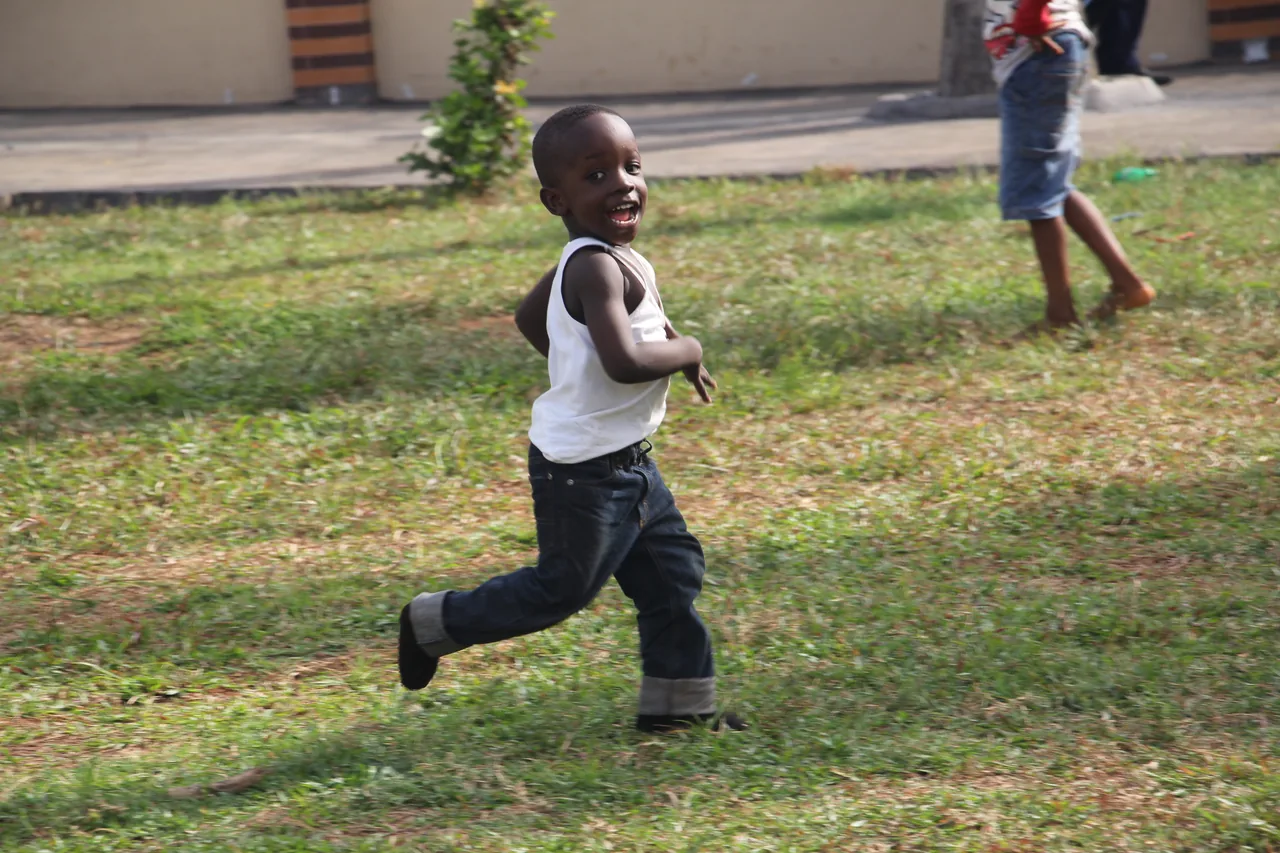 Niño corriendo sobre hierba como ejemplo de movimiento locomotor