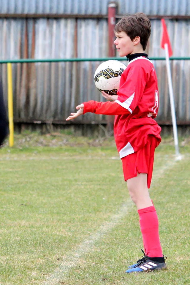 Joven futbolista con un balón entre las manos preparando un saque de banda
